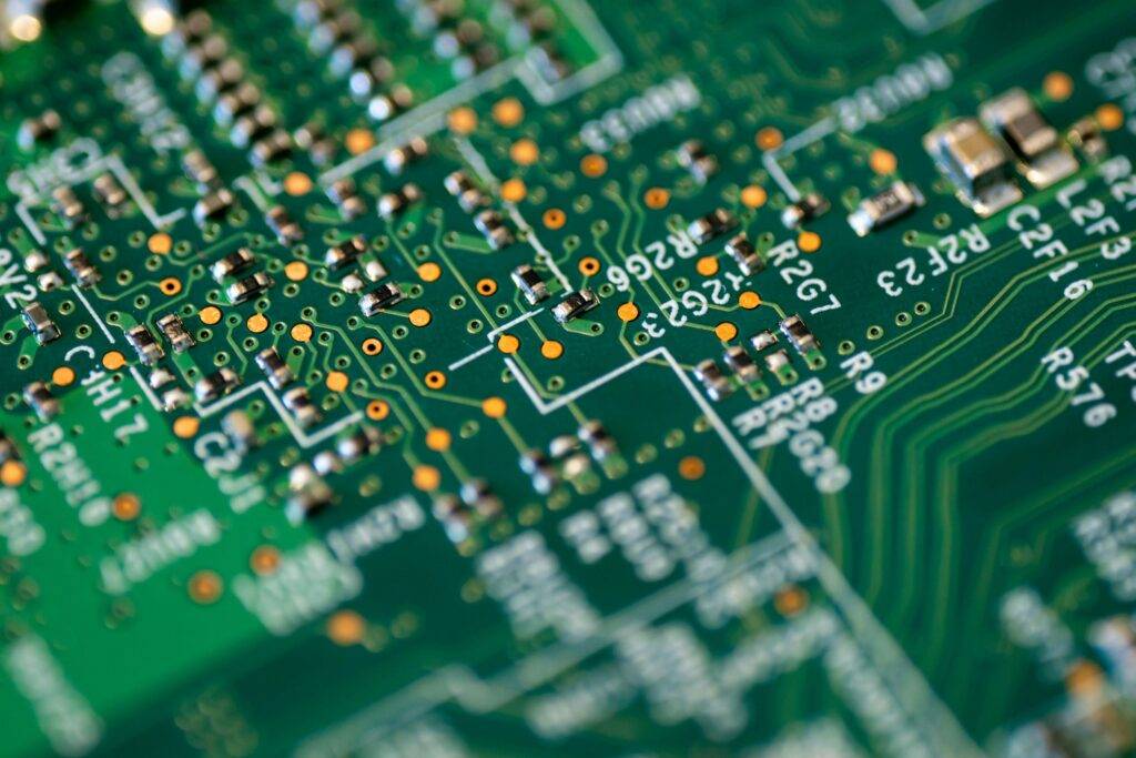 OpenSistemas - Consultora IT 177 Una placa de circuito impreso (PCB) en primer plano, con trazas metálicas y componentes electrónicos. Simboliza la base de la electrónica moderna, microchips y hardware para dispositivos tecnológicos.