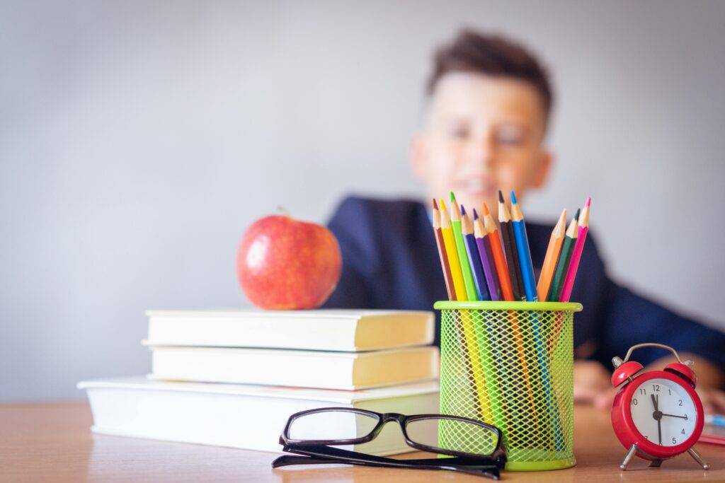 OpenSistemas - Consultora IT 67 Niño con útiles escolares, libros y colores sobre la mesa, representando el inicio del aprendizaje personalizado